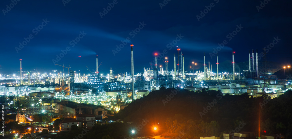 Fototapeta premium Large industrial petrochemical zone - oil refinery plant illuminates the night sky with glowing industry lights during oil production. 