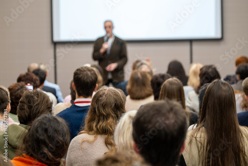 Wallpaper Mural Crowd of professionals listening to presenter during business conference, some attendees recording slides with smartphones. Torontodigital.ca