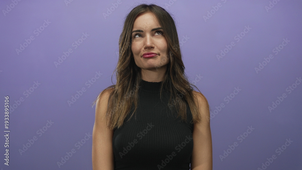 Naklejka premium Woman with wavy brunette hair smiles with pursed lips and tilts head gently in purple studio; playfulness curiosity spontaneity creativity.