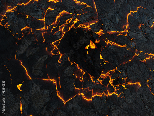 Aerial view of fiery lava flows seething through the dark, fractured earth, a stark contrast of molten orange against the cool, solid ground, Grindavik, Iceland.