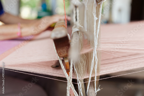 Thai woman weaving colorful silk fabric with ancient technique in rural village.