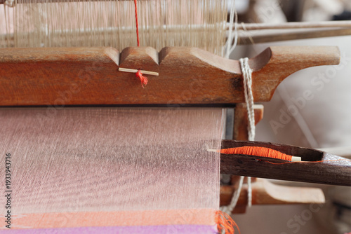 Thai woman weaving colorful silk fabric with ancient technique in rural village.