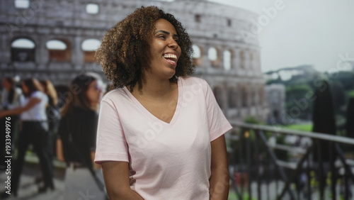 Photos Woman smiling and showing teeth in front of coliseum building, hands relaxed at sides; joy travel memory