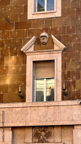 Architectural detail of historic Roman building facade with sculpture and decorative classical elements under blue sky in Rome, Italy.