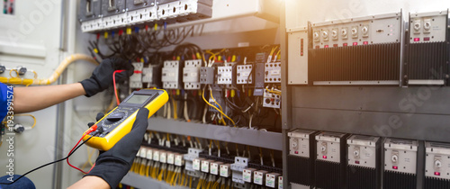Fotografie Electrical service technician use electricity measuring tools equipment checking electric current circuit breaker terminal panel and cable wiring main power distribution board for maintenance system