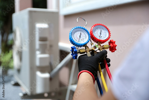 Foto Air conditioning electrical technician using manifold gauge measuring tool checking refrigerant pump filling home air conditioner and maintenance heat fix repair and clean outdoor compressor unit