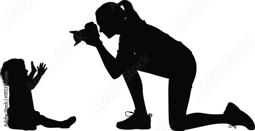 Black silhouette of a female photographer kneeling to take a photo of a small baby for family photography motherhood and professional creative studio concepts.