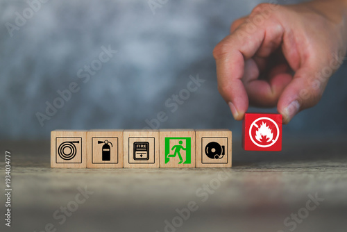 Hand choose cube wooden block stack with fire prevent icon and door exit sing or escape with fire extinguisher and emergency protection symbol for safety and rescue in the building.