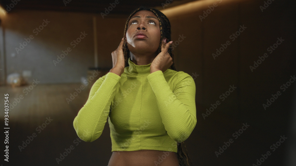 © Krakenimages.com - Woman covering ears with hands in studio wearing green crop top and braided hair, eyes closed and grimacing; ear pain distress. © Krakenimages.com - Woman covering ears with hands in studio wearing green crop top and braided hair, eyes closed and grimacing; ear pain distress.