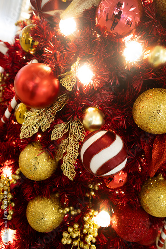 Close up red Christmas tree with red golden ball ornament and gold leaf decoration with light bulb