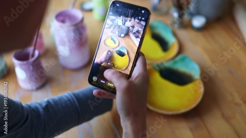 Artist photographing her products with a smartphone in a ceramics studio
