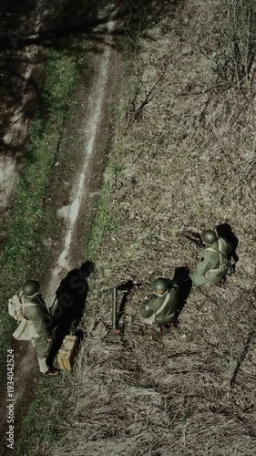 Aerial view of US WWII soldiers and medic patrolling a dirt path in Europe. Aerial view of US WWII mortar team positioning weapon near dirt road in the Netherlands