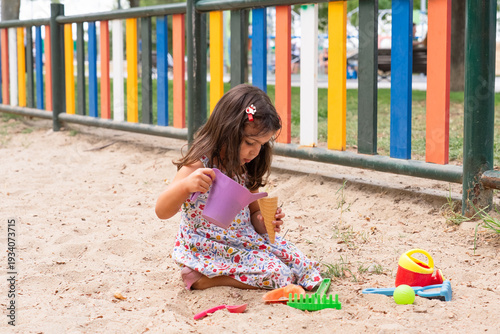Quadro su tela Little girl playing with colorful toys in sandbox