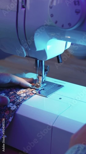Woman stitching floral fabric in blue light
