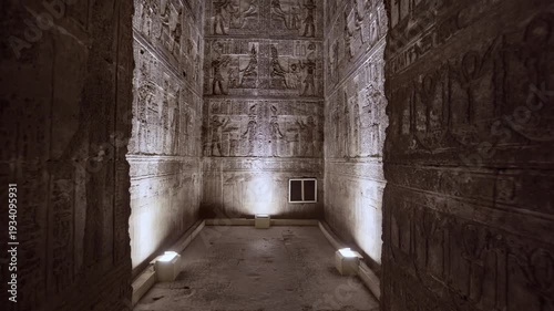 Dendera temple interior sanctuary with illuminated hieroglyphic walls and ritual reliefs in Egypt, ancient sacred chamber with dramatic lighting on carved sandstone surfaces.