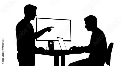 Two men discuss work on computer in office setting with monitor and laptop