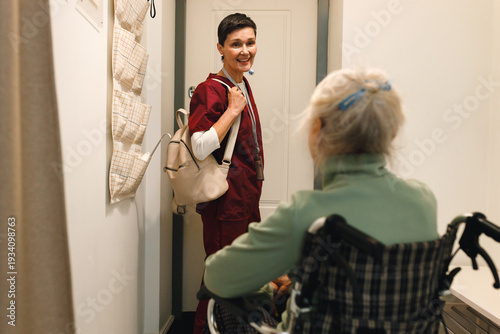 Photos Indoor picture of kinesiotherapist leaving place of her patient in wheelchair wi