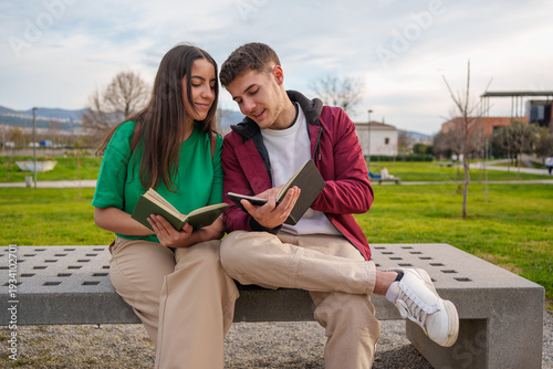 Students reading exploring book together on campus bench