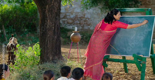 Obraz na plátně Indian mature adult teacher do study work teach to villager young girl boy rural