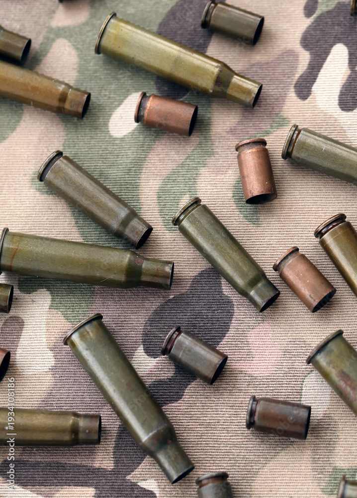 Obraz premium Big amount of shells cartridges from assault rifle bullets on old camouflage fabric