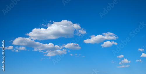Photography blue sky background with some fluffy floating cumulus clouds in the middle