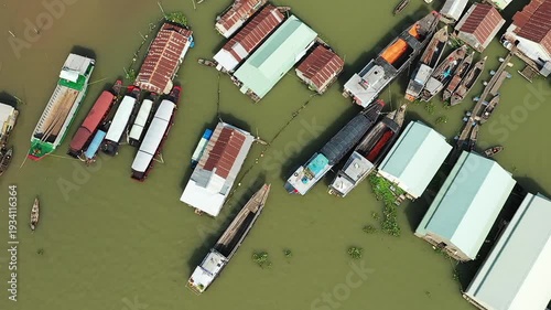 Aerial view of floating houses and boats on the river in Chau Doc, Vietnam, showcasing a unique riverside community. Traditional wooden boats and stilted structures are visible on the murky water.