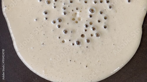 The pancake batter slowly flows down the pan.