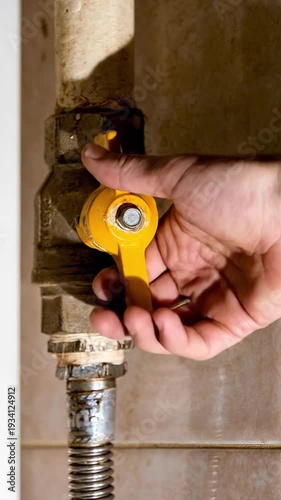 A hand turns over a household gas tap on a pipe