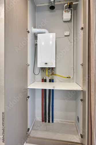 Gas boiler installed inside open utility cabinet