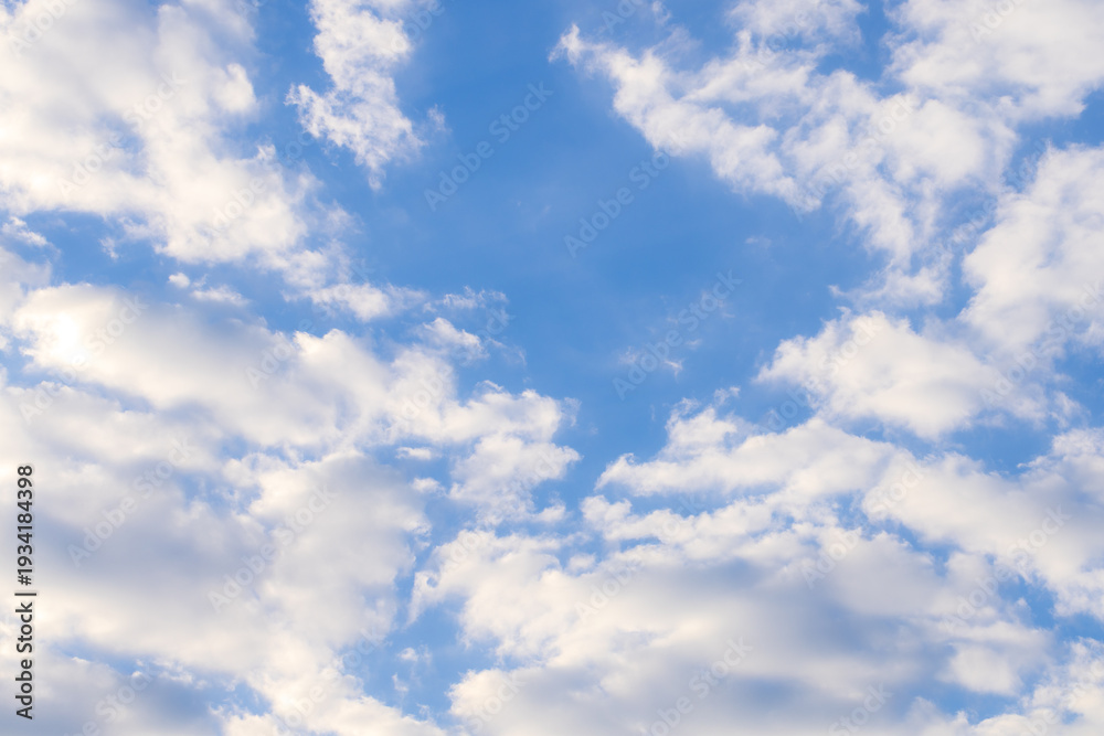 Obraz premium Soft white cumulus clouds on a clear blue sky background,A beautiful high-angle shot of fluffy white clouds scattered across a bright blue sky during a sunny day. This natural background is perfect.
