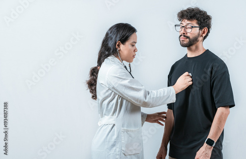 Young Asian doctor checking a male patient heart with a stethoscope, isolated. Asian doctor checking a patient heartbeat with a stethoscope