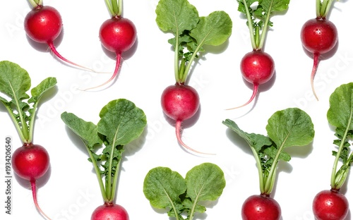 Fresh red radishes with green leaves scattered on a white background.