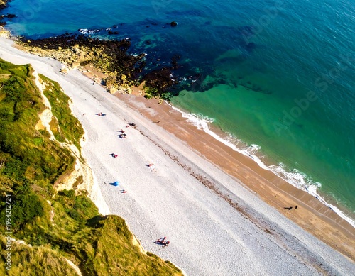 Wallpaper Mural Aerial view of a stunning coast scene with a white pebble beach meeting crystal-clear, turquoise waters. Tall cliffs flank Torontodigital.ca