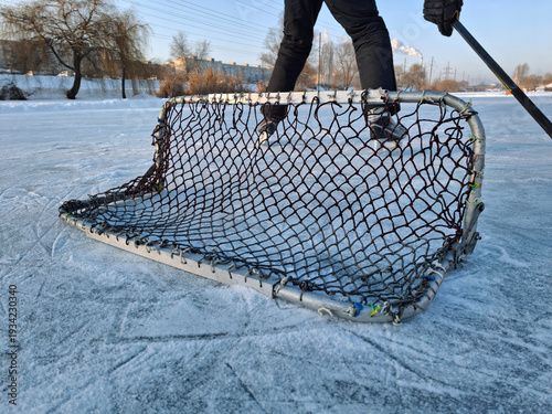 Canvas Print A hockey player stands on a frozen lake near a goal