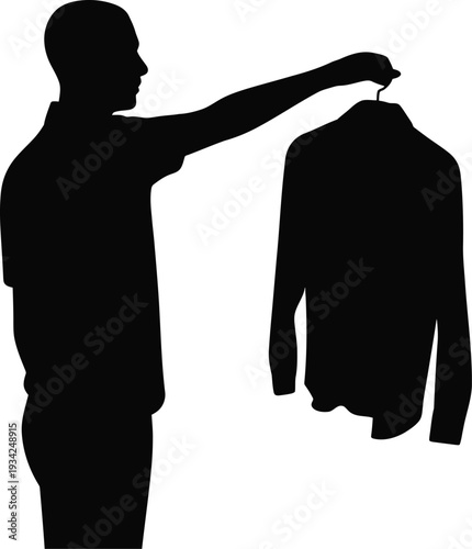 Silhouette of person holding up a shirt on hanger to inspect
