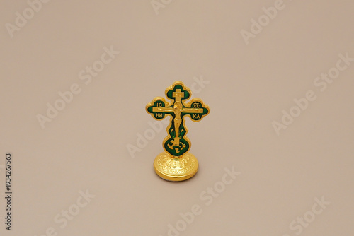 Obraz na płótnie An ornate, gold and green Eastern Orthodox crucifix stands isolated against a plain, neutral beige background