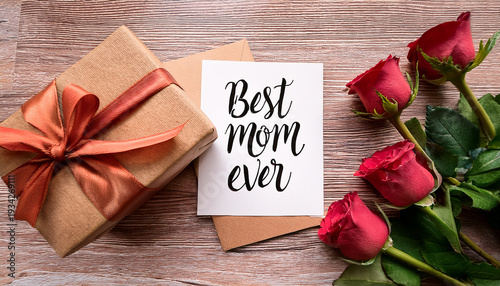 Gift box and greeting card with flowers on wooden table for special occasion Generative AI