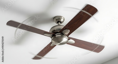 Ceiling fan with brown wooden blades and silver hardware spinning on white ceiling