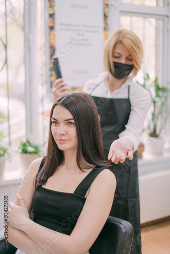 Professional hairdresser woman in an apron makes a haircut to a young girl in a beauty salon. Free Download Professional hairdresser woman in an apron makes a haircut to a young girl in a beauty salon. - GFXLoad