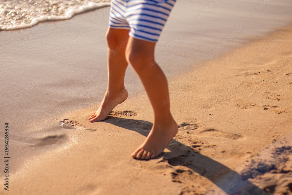 Naklejka premium Child legs walking in wet sand