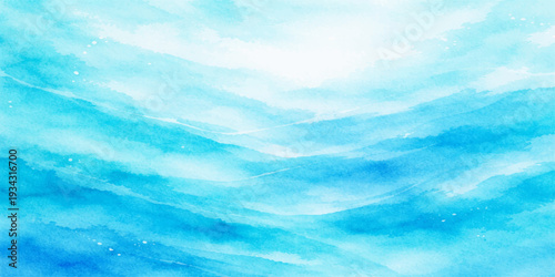 A beautiful summer landscape of white clouds in a bright blue sky reflecting over the calm ocean water and light waves at the horizon