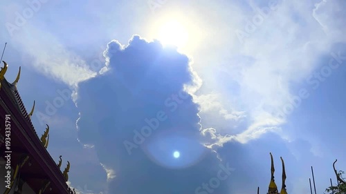 The Sun's Shining Behind Big Cloud and Parts of Roofs of Temple on Blue Sky Background Compound of a Monastery at Bangkok, Thailand. 19 MAY 2025, A.M./ Speed Up Video