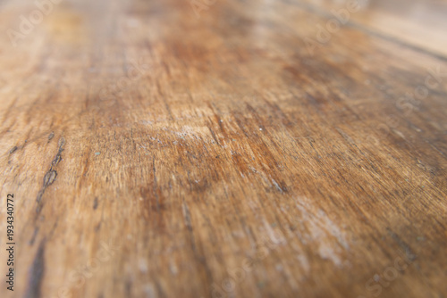 Rustic wooden surface, close-up. Brown tones, natural grain, visible texture. Shallow depth blurs background. 