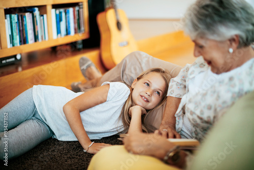Fotografie Grandmother and granddaughter relaxing and talking in living room