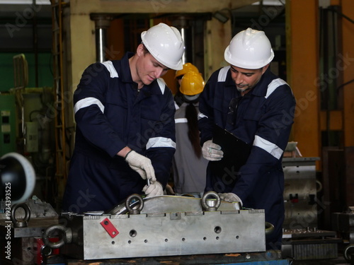 Team of engineers inspecting automotive parts in industrial factory