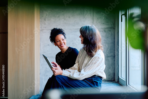 Obraz na plátně Two diverse business women collaborating and discussing content on a digital tab