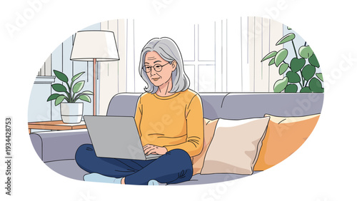 Mature woman wearing glasses sitting comfortably on her sofa while using a laptop for work or entertainment in her bright living room.