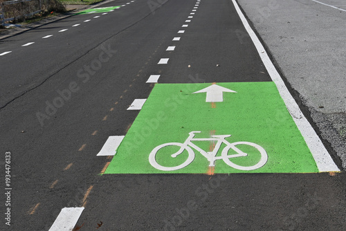 Green paint with white bicycle symbol and arrow for bike lane on road
