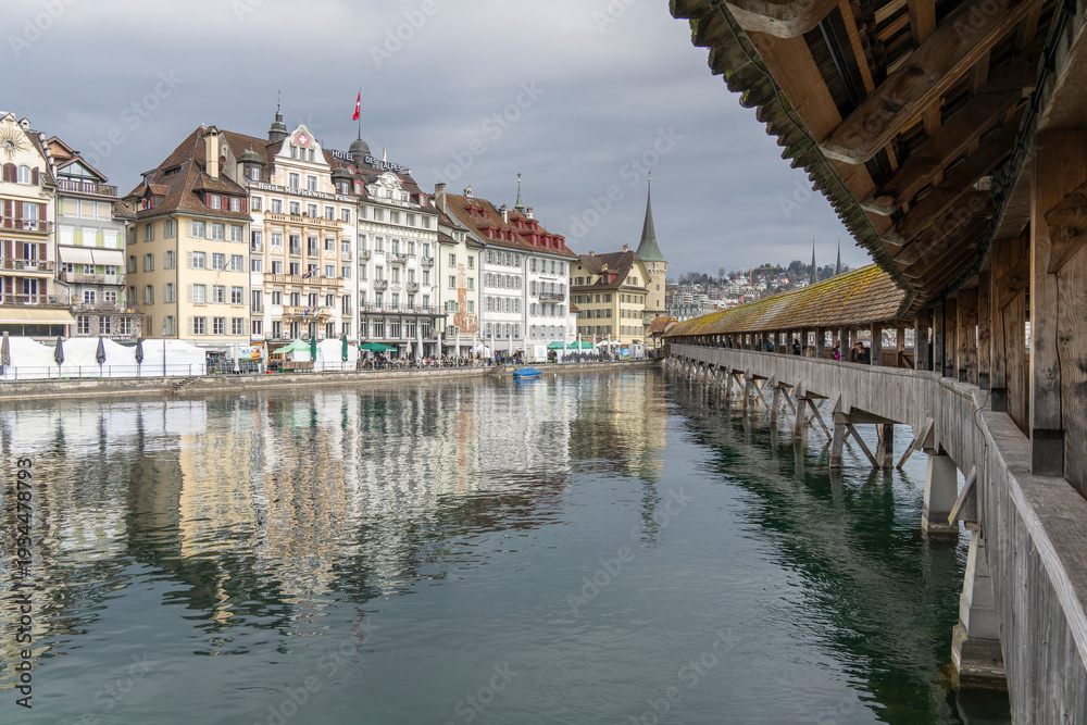 Obraz premium medieval wooden bridge with tower, mirroring in the water, center of Lucerne, a landmark of the city, old town of Lucerne, Switzerland, surrounded by beautiful old houses with shutters and paintings.