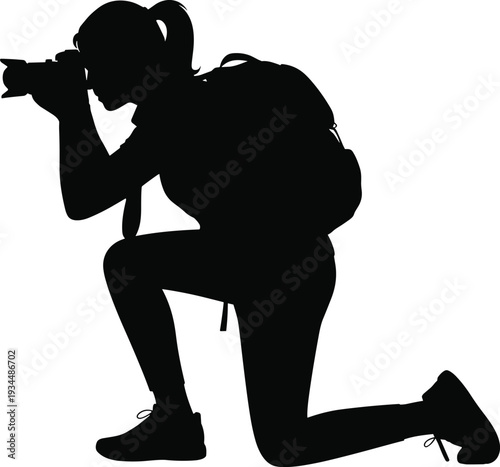 Black silhouette of a female photographer with a backpack kneeling to take a photo for travel journalism outdoor adventure and creative hobby lifestyle concepts.